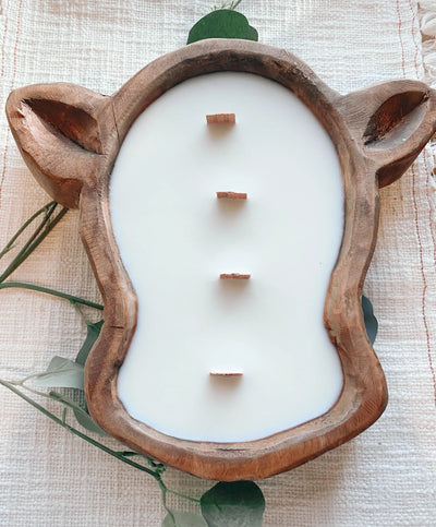 Plain cow head dough bowl candle sitting on table.