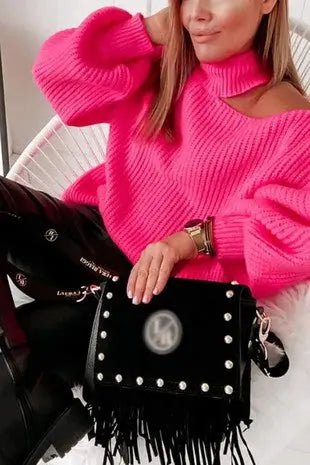 Woman wearing a hot pink shoulder cutout puffy sleeve sweater while sitting down comfortably. 